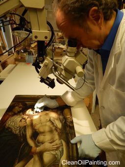 Art conservator Bruce Wood using a microscope to repair a centuries-old oil painting